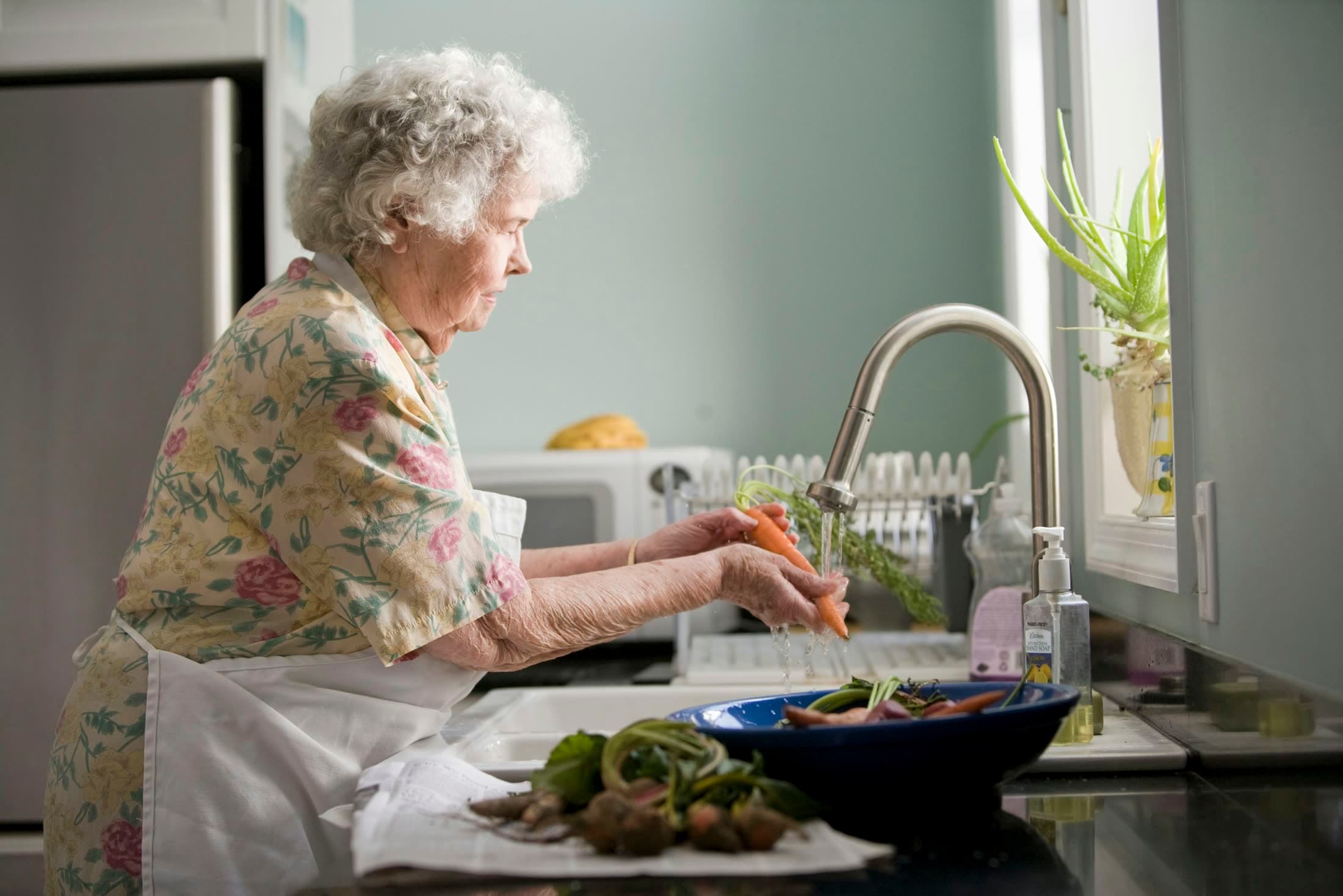 Seniorin bereitet in ihrer Küche Gemüse zu